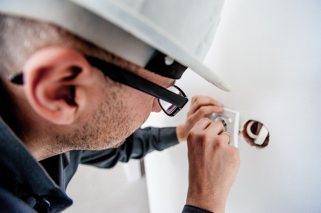 A electrician changing the position of a power outlet, showing one of the home improvements that require a permit.