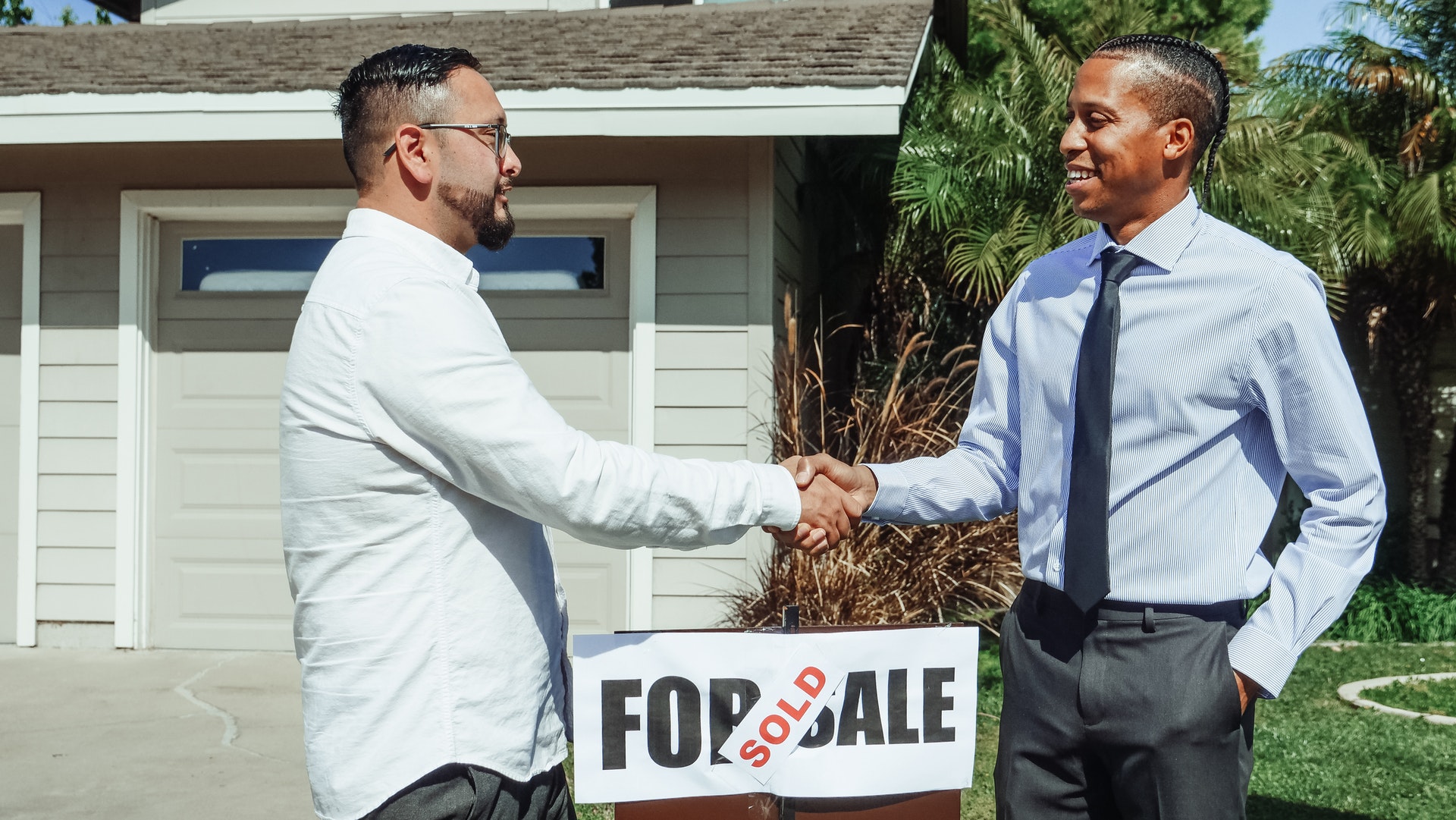 A person shaking hands with a home seller, showing the main benefit of waiving a home inspection