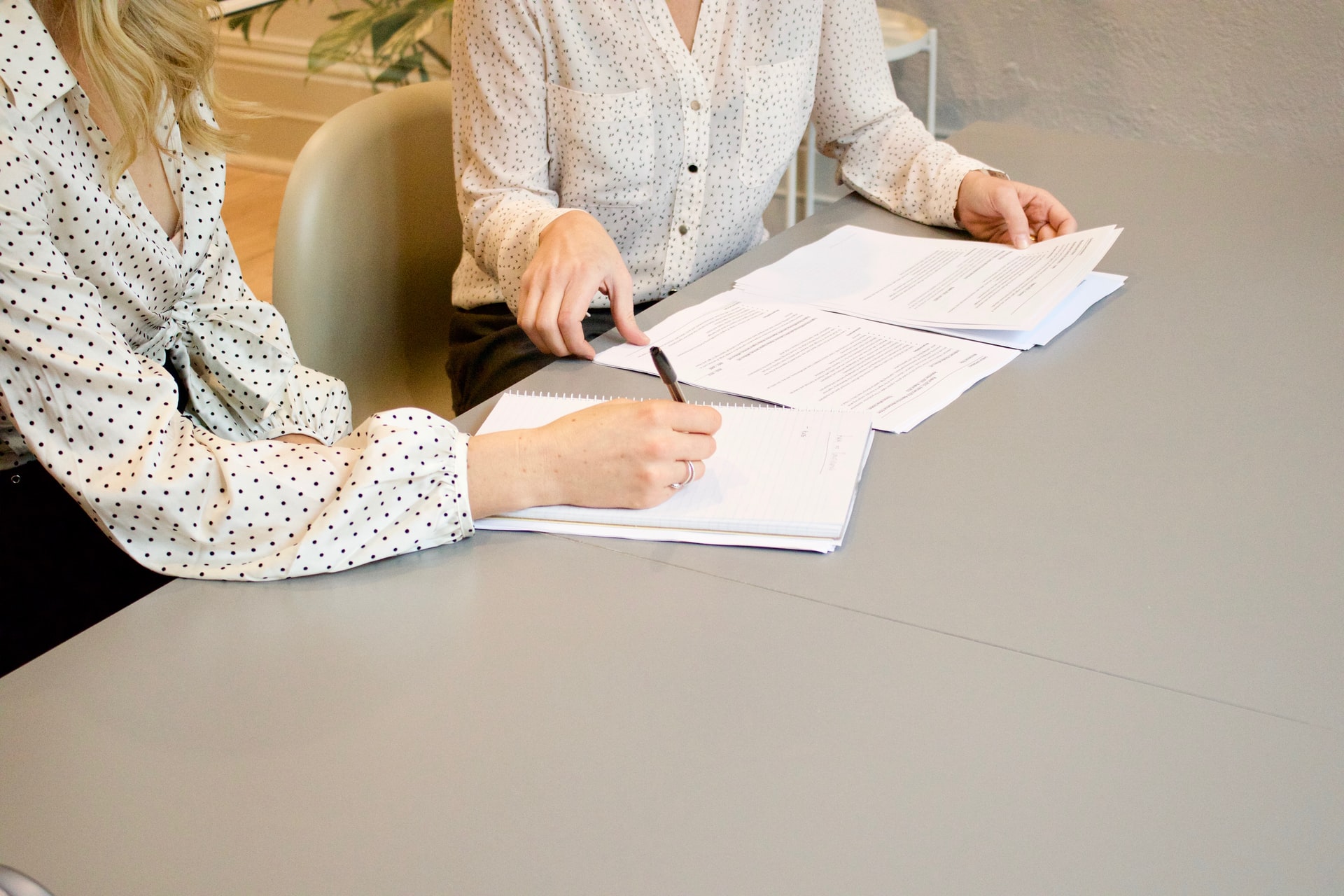 Two women signing a contract.