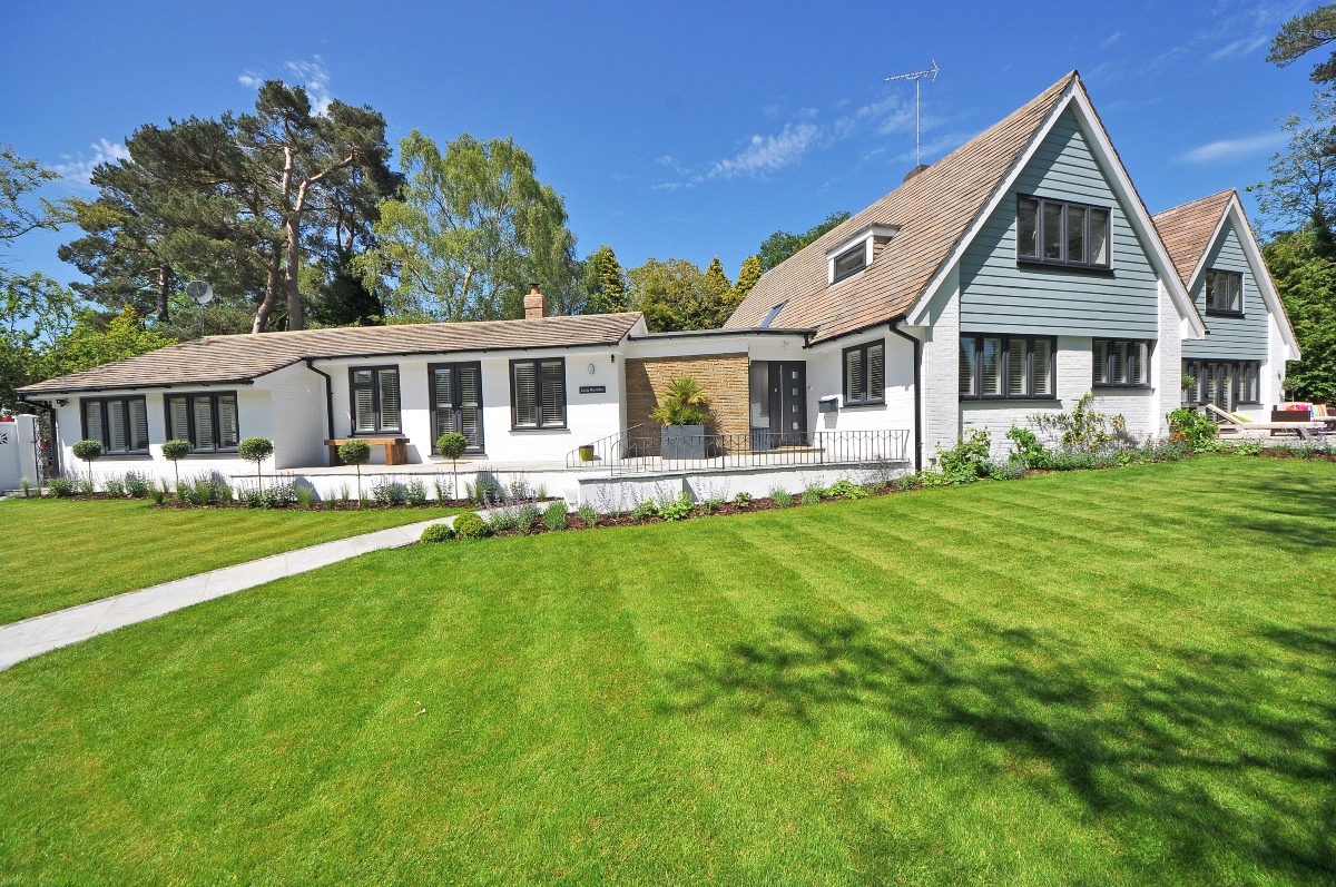 A huge house with white and light blue walls, black windows, and a light brown roof.