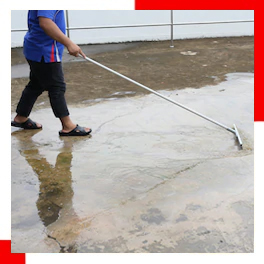 Technician performing water damage restoration with a floor squeegee on a wet surface