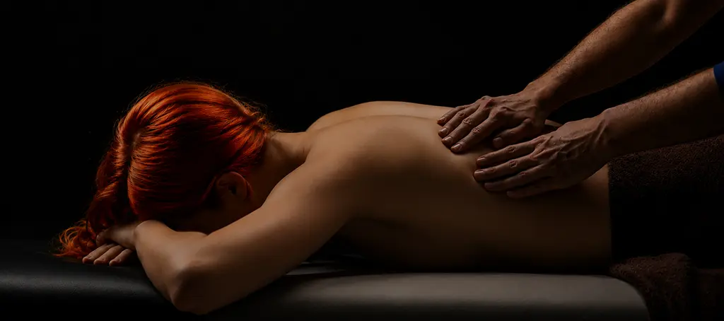 Licensed massage therapist performing back pain massage therapy on a female client, addressing mid back and lumbar tension at Elite Healers Sports Massage, a clinical sports massage and performance recovery practice serving Midtown Manhattan professionals and NYC athletes dealing with chronic back pain, located at 120 East 56th Street, Suite 420, New York, NY 10022