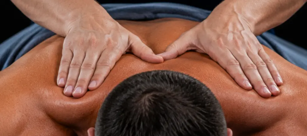 Licensed Elite Healers Sports Massage therapist providing a two-hand palm compression across the upper back and shoulders for a client at Elite Healers Sports Massage, located at 120 East 56th Street, Suite 420, New York, NY 10022