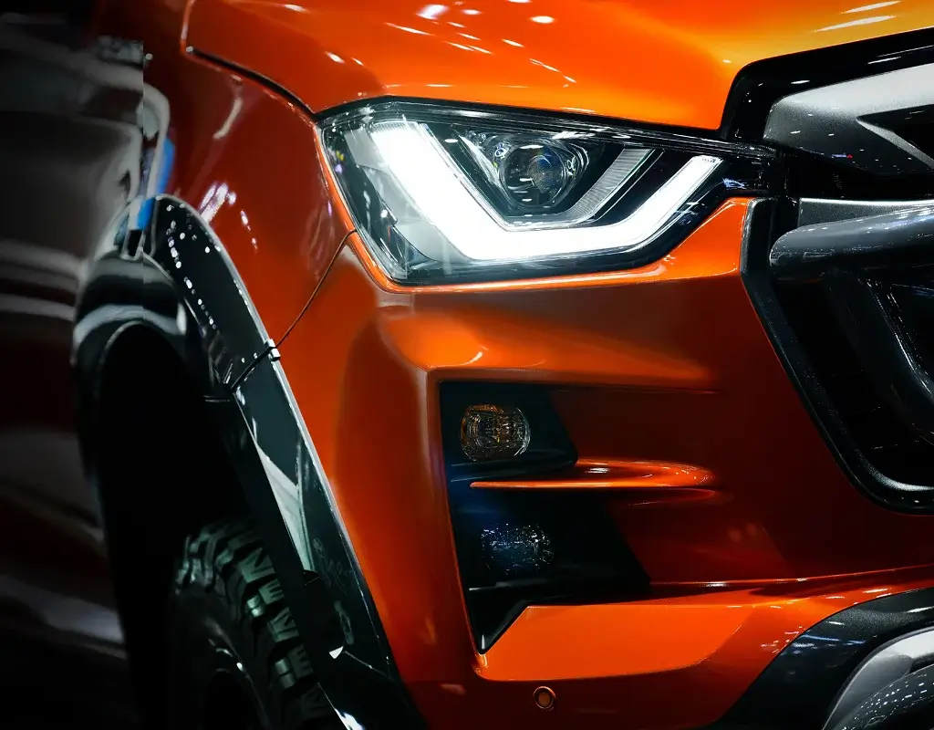 Close-up of an orange colored vehicle headlight and front bumper at an Auto Body Shop in Merriam
